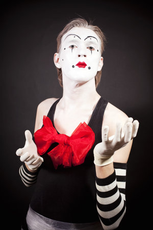 Mime with a red bow in striped  gloves on black backgroundの写真素材