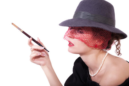 Retro portrait of young woman in a hat and veil with cigaretteの写真素材