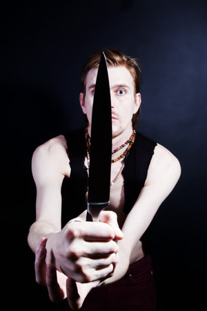 young man attacking with knife on black backgroundの写真素材