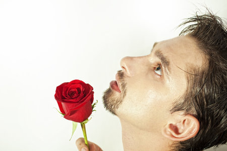 Profile of young men smell the red rose isolated on white backgroundの写真素材