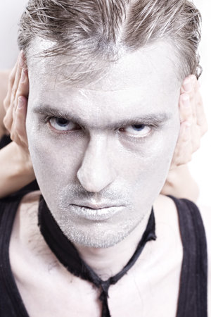 Portrait of young man closed his ears with silver makeupの写真素材