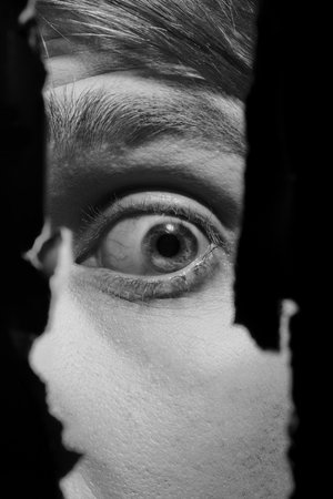 Scary eyes of a man spying through a hole in the wallの写真素材