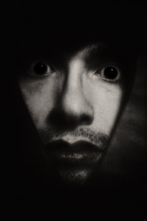 Face of young man peering from hole close upの写真素材