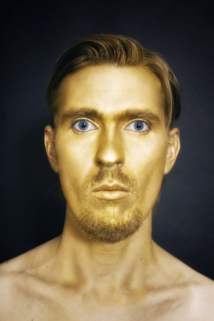 young attractive blue-eyed men with gold makeup on her face and stylish hairstyle on black backgroundの写真素材