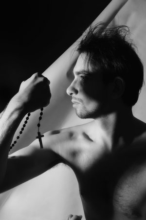 Portraits of a beautiful young man with a rosary in his handsの写真素材