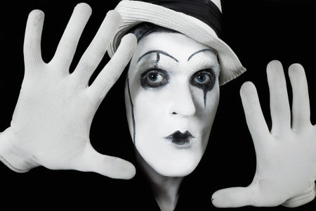 face and hands of mime with dark make-up on black backgroundの写真素材