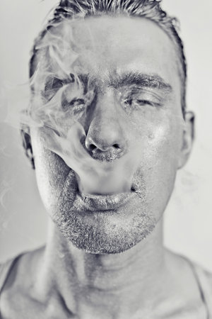 monochrome portrait of young attractive man with a silvery makeu in the smokeの写真素材