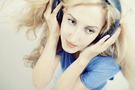 young woman singing with headphones isolated on light backgroundの写真素材