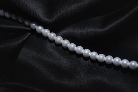 white pearl necklace on a black silk close upの写真素材