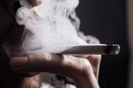 smoking cigarette in the hand of young man close upの写真素材