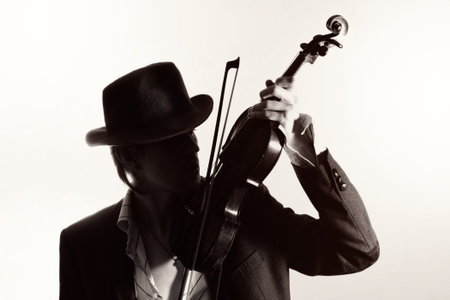 young violinist playing the violin in hat and jacket  on a light backgroundの写真素材