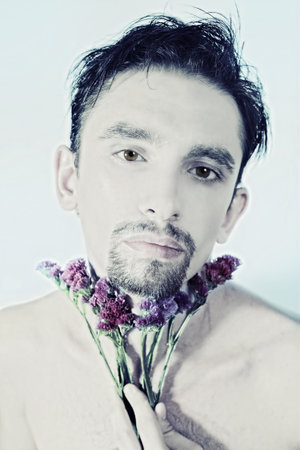 Face of young man with purple flower on light backgroundの写真素材