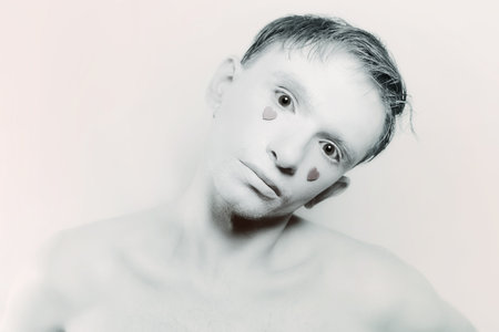 young man with white makeup and red hearts instead of tearsの写真素材