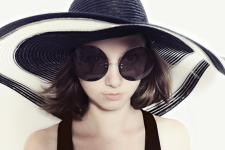 Portrait of a young girl in a big round sunglasses and summer hatの写真素材