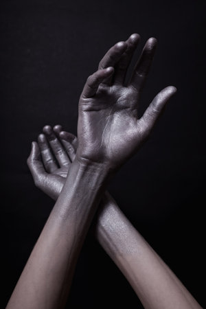 beautiful man's hands in gold paint on black background close upの写真素材