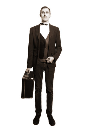 Retro portrait of a young man standing on a white background, with a suitcase isolated on white backgroundの写真素材