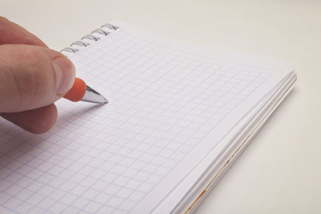 Male hand holding a ballpoint pen and notepad
