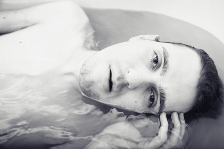 young sexual tanned naked guy in bath close upの写真素材