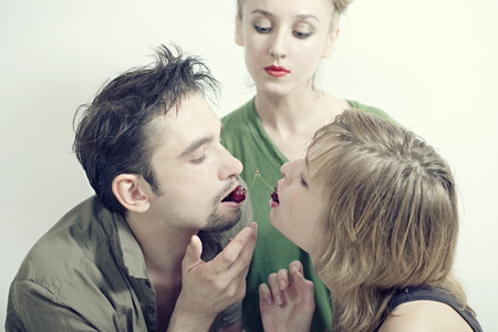Two women and one man with the red ripe cherries closeupの写真素材