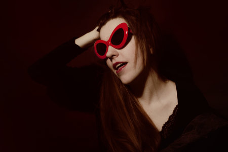 Young woman in red sunglasses on a black backgroundの写真素材
