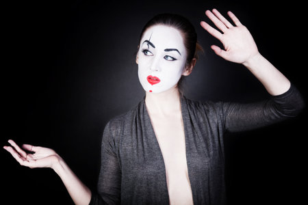 A woman in a theatrical mime make-up dancing on a black backgroundの写真素材