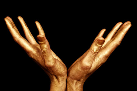 Two male hands in gold paint isolated on a black backgroundの写真素材