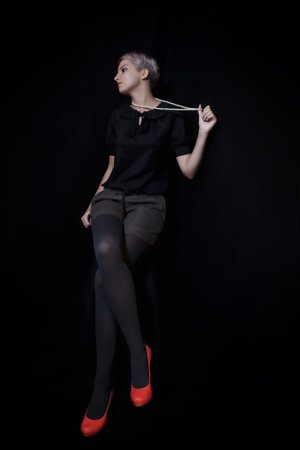 Beautiful young woman with short hair sitting on a black backgroundの写真素材