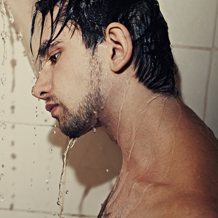 Portrait of a young handsome man takes a shower closeupの写真素材