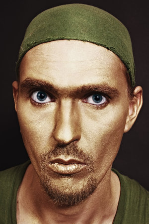 young attractive blue-eyed men with gold makeup in green headscarf closeupの写真素材