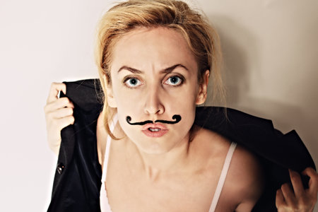 Portrait of young woman with painted mustache wearing jacketの写真素材
