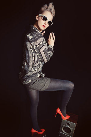 Stylish woman standing on a musical speakers on the black backgroundの写真素材