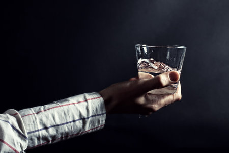 Hand holding a clear glass of water on a black background close upの写真素材