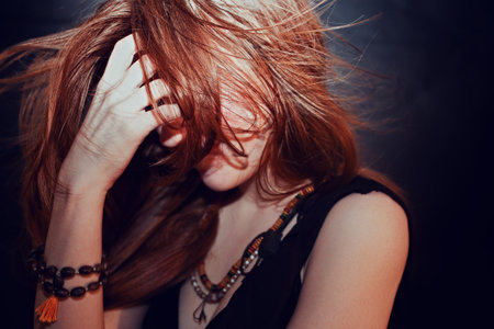 Red-haired young girl with hair fluttering in the windの写真素材