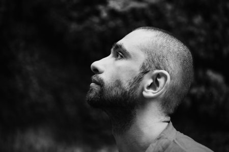 Portrait of  young sad man with short hair in forestの写真素材