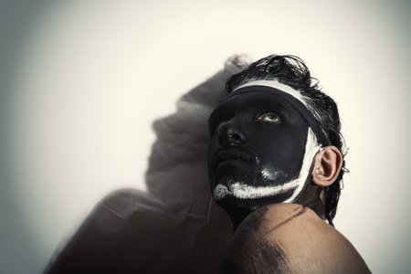 Portrait of man with black theatrical makeup on white backgroundの写真素材