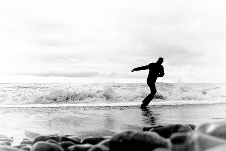 Silhouette of a young man running along the seashoreの写真素材
