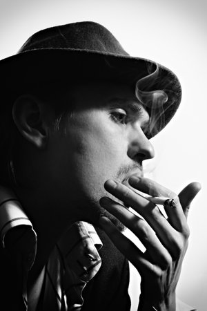 Black and white portrait of a young  smoking man wearing a hat