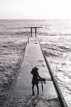 young woman in a coat with an umbrella on the pierの写真素材