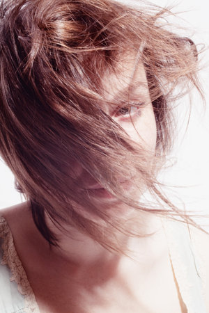 Portrait of a beautiful young woman with hair in the windの写真素材