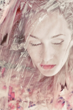 Portrait of a beautiful woman through the dirty glass closeup