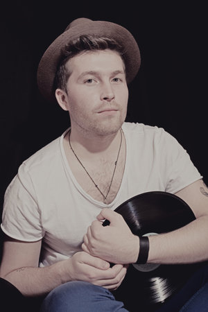 Portrait of a young man with a vinyl record on a black background
