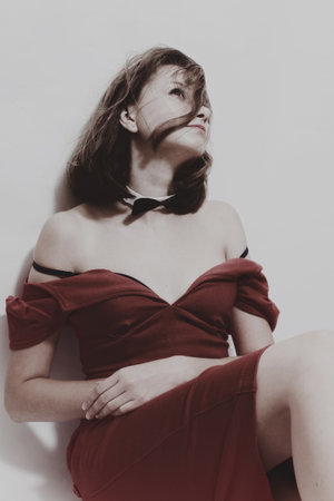 Studio portrait of a beautiful young woman in a red dress on lighte  backgroundの写真素材