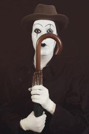 Stage actor with makeup mime in a hat holding an umbrella in his handの写真素材
