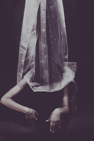 Woman with face hidden behind a white clothの写真素材