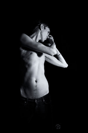 young slender naked man on a black backgroundの写真素材