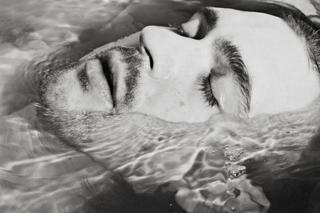 Face of the young men in bath with crystal clear waterの写真素材