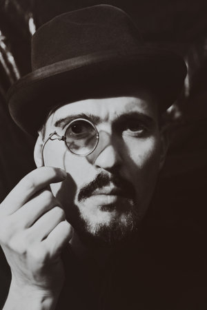 Retro portrait of an adult man wearing a hat and holding a pince-nezの写真素材