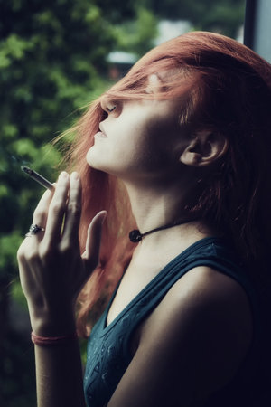 Portrait of young beautiful girl with cigarette in hand