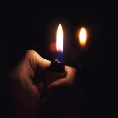 Male hand holding a burning lighter in the darkの写真素材