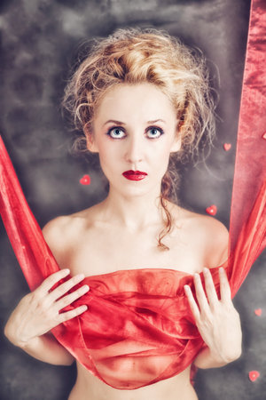 Portrait of young beautiful naked woman with a piece of red clothの写真素材